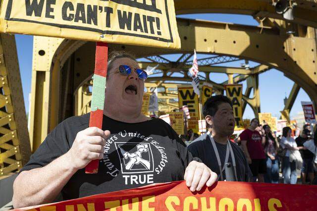 A woman wearing a Twin Rivers United Educators T-shirt participates in a joint march with Natomas teachers across Tower Bridge in Sacramento on Thursday as a part of their strike against their respective districts.
